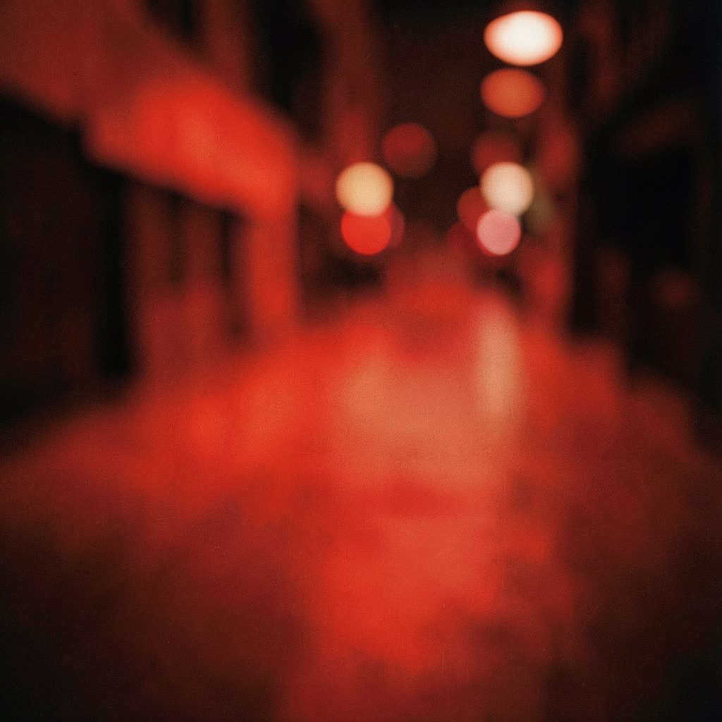 Wide cinematic frame of recruiter booths lined up under gallery lighting, muted reds and creams, shallow depth of field.